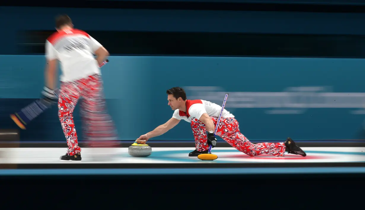 Atlet curling Norwegia, Thomas Ulsrud tampil bertanding melawan Amerika Serikat pada perhelatan Olimpiade Musim Dingin Pyeongchang 2018, Minggu (18/2). Atlet curling tersebut mengenakan celana merah bergambar bunga biru dan putih. (AP/Aaron Favila)