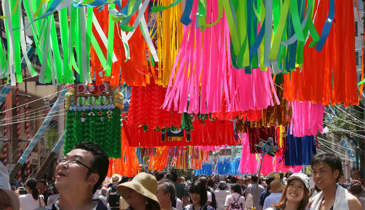 Sepasang kekasih berswafoto di bawah hiasan The Star Japan Festival di sepanjang jalan Hiratsuka, Tokyo, Jumat (7/7).  Festival bintang ini juga dikenal dengan nama Tanabata yang berarti Malam Ketujuh. (AP/Koji Sasahara)