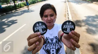 Seorang pemudi menunjukkan PIN berlogo kawan8 saat Car Free Day di kawasan Senayan, Jakarta Minggu (24/7). Mereka juga mengajak masyarakat untuk bisa berlaku adil dalam segala hal. (Liputan6.com/Fery Pradolo)