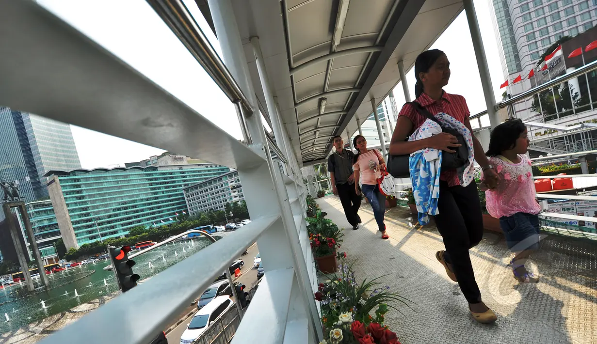 Warga berjalan menggunakan jembatan penyebrangan orang (JPO)  Bundaran HI, Jakarta, Jumat (20/3/2015). Pemprov DKI akan menjadikan JPO di kawasan Bundaran HI sebagai standar JPO yang ada di Jakarta nanti. (Liputan6.com/Faizal Fanani)