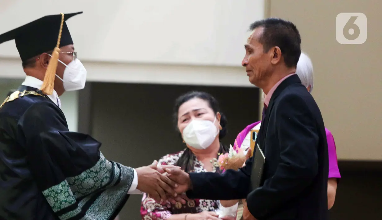 Ayah Brigadir Nofriansyah Yosua Hutabarat atau Brigadir J, Samuel Hutabarat (kanan) menerima ijazah dari Rektor Universitas Terbuka Ojat Darojat saat mewakili anaknya mengikuti prosesi wisuda di Universitas Terbuka, Pamulang, Tangerang Selatan, Banten, Selasa (23/8/2022). Brigadir J lulus memuaskan dengan IPK 3,28. (Liputan6.com/Herman Zakharia)