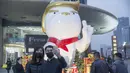 Sepasang pengunjung berswafoto dengan latar belakang patung anjing raksasa mirip Presiden AS Donald Trump di Festival Walk Mall, Shanxi, Tiongkok, Jumat (29/12). Keberadaan patung ini untuk menyambut datangnya tahun anjing tanah. (STR / AFP)