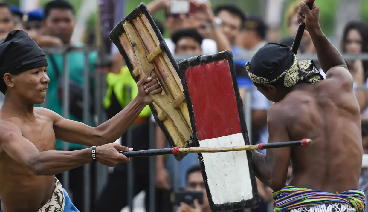 Dua pepadu (petarung) melakukan duel dalam kesenian tradisional peresean di Praya, Lombok Tengah, Selasa (19/2). Peresean merupakan kesenian tradisional suku Sasak yang dulunya diadakan setiap musim kemarau panjang. (MOH EL SASAKY/AFP)