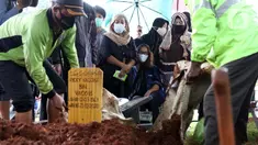 Istri mantan penggawa Timnas Indonesia Ricky Yacobi, Harly Ramayani (duduk tengah) menyaksikan proses pemakaman suaminya di TPU Tanah Kusir, Jakarta, Sabtu (21/11/2020). Ricky Yacobi meninggal dunia pada Sabtu (21/11) akibat serangan jantung pada usia 57 tahun. (Liputan6.com/Helmi Fithriansyah)