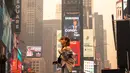 Seorang pejalan kaki berpose untuk berfoto di Times Square di tengah kabut asap dari kebakaran hutan dari Kanada, di New York City, Rabu (7/6/2023). (David Dee Delgado/Getty Images/AFP)