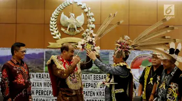 Wakil Ketua DPD Nono Sampono (kedua kiri) menerima pakaian adat untuk prajurit dari Tokoh Adat Dayak di Kompleks Parlemen Senayan, Jakarta, Selasa (19/9). (Liputan6.com/Johan Tallo)