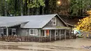 Banjir dari Danau Madrone mengalir melewati sebuah rumah di Oro Quincy Highway di Butte County, California, Minggu (24/10/2021). Badai kuat menerjang California Utara yang sempat mengalami kebakaran hutan, memicu tanah longsor dan banjir, juga membawa angin kencang. (AP Photo/Noah Berger)