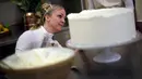 Pemilik Violet Bakery, Claire Ptak memberi sentuhan akhir pada kue pengantin Pangeran Harry dan Meghan Markle di dapur Istana Buckingham, London, Kamis (17/5). Harry dan Meghan akan menikah pada 19 Mei mendatang di Windsor Castle. (HANNAH MCKAY/POOL/AFP)