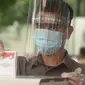 Petugas memakai face shield memasukan surat pemungutan suara dalam pemilihan serentak 2020 saat simulasi di Halam Kantor KPU, Jakarta, Rabu (22/7/2020). Simulasi pemungutan suara di TPS dengan menerapkan protokol kesehatan Covid-19. (merdeka.com/Imam Buhori)
