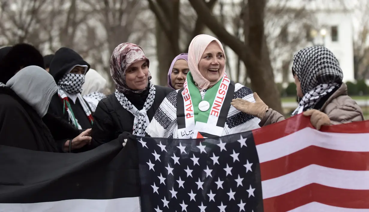 Warga Muslim berkumpul menggelar aksi protes di depan Gedung Putih, Washington DC, AS, Jumat (8/12). Beberapa dari mereka mengenakan syal keffiyeh khas Palestina atau memakai warna-warna yang menyimbolkan bendera Palestina. (Eric BARADAT / AFP)