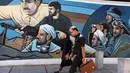 Pejalan kaki melewati mural yang menggambarkan sejumlah pria dengan senjata di Palestine Square, Ibu Kota Teheran, Iran, Sabtu (22/6/2019). (ATTA KENARE/AFP)