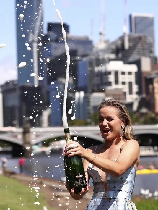 Petenis asal AS Sofia Kenin menyemprotkan sampanye pada sesi pemotretan di Sungai Yarra setelah kemenangannya atas Garbine Muguruza dari Spanyol di final tunggal putri kejuaraan tenis Australia Terbuka di Melbourne, Australia, Minggu, (2/2/2020). (AP Photo/Dita Alangkara)
