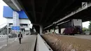 Pejalan kaki melintas dekat bus premium Transjakarta atau Royaltrans yang sedang menunggu penumpang di pul Royaltrans di kolong Tol Simatupang, Jakarta, Selasa (23/4). Dua rute bus Royaltrans berangkat dari pul ini, yakni S12 (BSD-Fatmawati) dan S31 (Blok M-Bintaro). (Liputan6.com/Herman Zakharia)