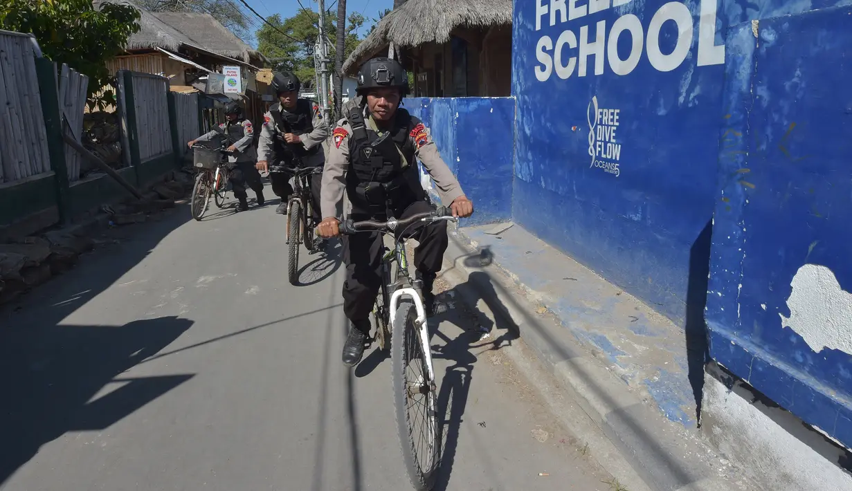 Polisi bersepeda berpatroli di kawasan wisata Pulau Gili Air, Lombok, Nusa Tenggara Barat (NTB), Sabtu (11/8). Patroli dilakukan setelah gempa 7 skala Richter melanda Lombok pada 5 Agustus lalu. (Adek BERRY/AFP)