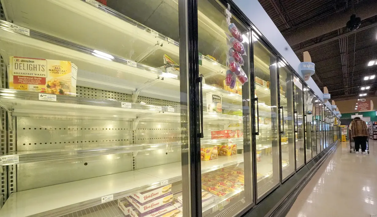 Seorang pembeli melewati pendingin makanan beku yang sebagian kosong di sebuah toko di Cranberry Township, Pennsylvania, Selasa (11/1/2022). Supermarket di Amerika Serikat (AS) tengah kekurangan produk bahan makanan karena tingginya penyebaran varian omicron dan cuaca buruk (AP Photo/Gene J. Puskar)