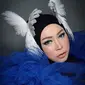 Wanita berusia 45 tahun ini tampil menggunakan headpiece berbentuk burung cendrawasih berwarna putih dipadukan dengan hijab berwarna hitam dan baju warna biru yang mengembang. (Liputan6.com/IG/@melly_goeslaw)