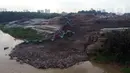 Foto udara memperlihatkan alat berat memindahkan tumpukan sampah dari Tempat Pembuangan Akhir (TPA) Cipeucang yang masuk ke area Sungai Cisadane, Serpong, Tangerang Selatan, Rabu (3/6/2020). Sebelumnya, pada Jumat (22/5/) lalu turap yang menopang TPA tersebut jebol. (Liputan6.com/Helmi Fithriansyah)