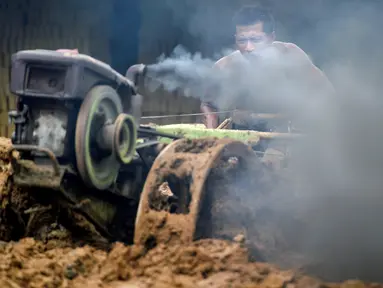 Seorang pria mencampur bahan untuk membuat batu bata di sebuah pabrik batu bata di pinggiran Kajhu, Provinsi Aceh (18/11/2020). (AFP/Chaideer Mahyuddin)