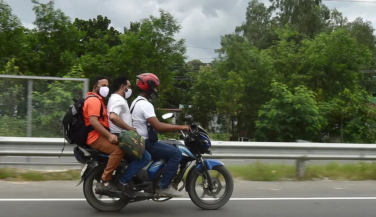 Orang-orang mengendarai sepeda motor menuju kampung halaman mereka setelah pelonggaran lockdown nasional COVID-19 di Sreenagar, Selasa (13/7/2021). Pemerintah Bangladesh telah memutuskan melonggarkan lockdown selama seminggu mulai 15 hingga 22 Juli untuk perayaan Idul Adha. (Munir Uz zaman/AFP)
