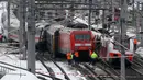 Regu penyelamat berdiri dekat dua rangkaian kereta penumpang yang terlibat tabrakan dekat stasiun di Niklasdorf, Austria, Senin (12/2). Tabrakan kereta itu menyebabkan satu orang tewas dan 22 lainnya terluka, tiga di antaranya anak-anak. (AP/Ronald Zak)