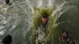 Cuaca yang panas dimanfaatkan oleh sejumlah warga di India untuk mandi di sungai, India, Rabu (5/4). Meski air sungai telah tercemar tidak menghalangi mereka untuk tetap mandi di sungai tersebut. (AFP PHOTO / ARUN SANKAR)