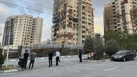 Warga mengamati apartemen yang rusak di Teheran, Iran, akibat serangan udara Israel pada Jumat (13/6/2025). (Dok. AP/Vahid Salemi)