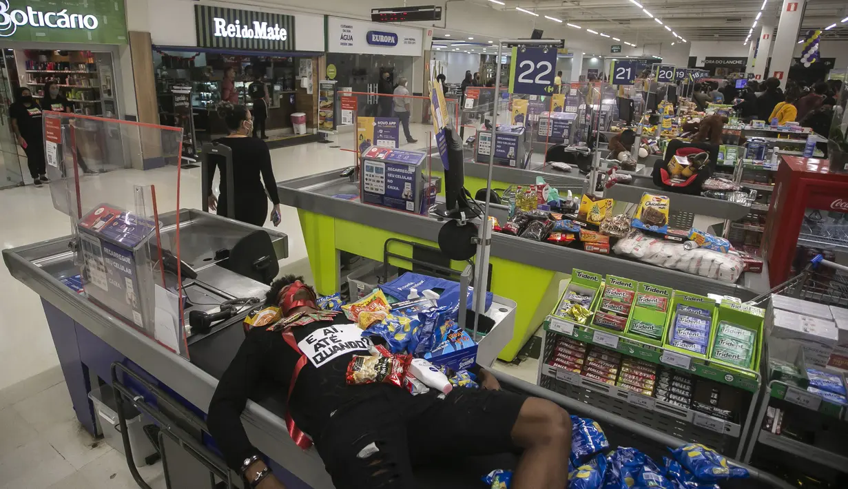 Jonata Anjo berbaring di kasir di supermarket Carrefour selama protes terhadap pembunuhan pria kulit hitam Joao Alberto Silveira Freitas di supermarket Carrefour, pada Hari Kesadaran Kulit Hitam Nasional Brasil di Rio de Janeiro, Brasil (20/11/2020). (AP Photo/Bruna Prado)