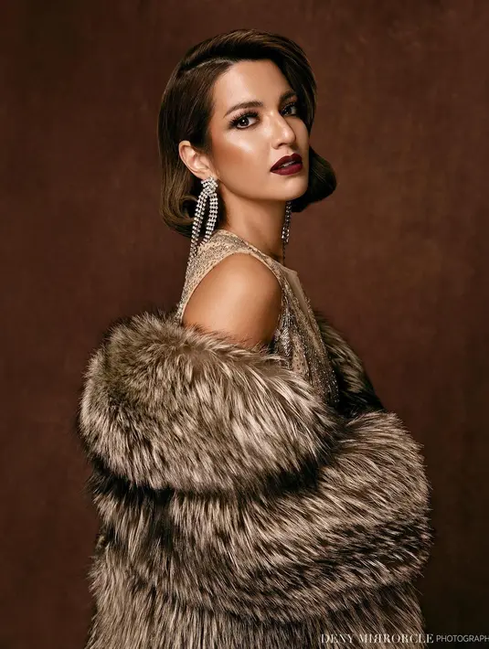 Dengan gaya klasik, wajah Nia Ramadhani dipulas dengan makeup bernuansa bold yang berani. Detail dramatis di bagian mata dan bibir gelap yang fierce. Sementara rambut pendek Nia Ramadhani ditata dengan flowy khas era 80an. (instagram/denymirrorcle)