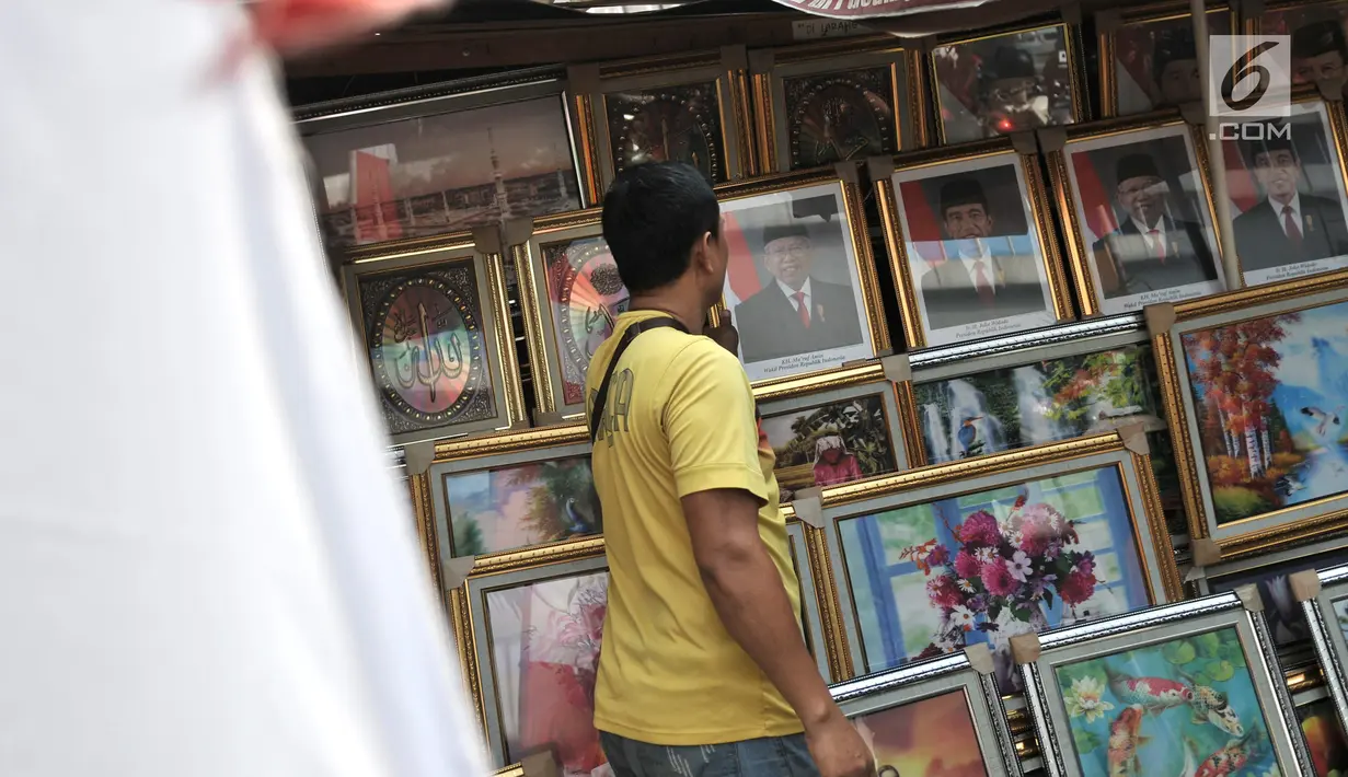 Pedagang merapikan foto Presiden-Wapres 2019-2024, Joko Widodo-KH Ma'ruf Amin di salah satu toko di Pasar Baru, Jakarta, Senin (26/8/2019). Foto Presiden dan Wapres Terpilih dijual Rp 200 ribu hingga Rp 900 ribu per paket (foto presiden dan wakil presiden). (merdeka.com/Iqbal S. Nugroho)