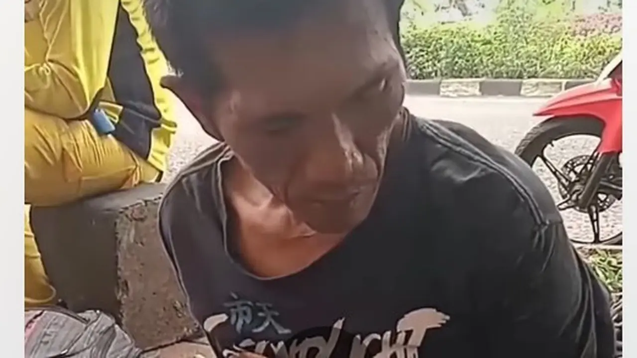 Seorang pria berkaos hitam tertunduk lesu saat diinterogasi di trotoar Jalan Basuki Rahmat, Kelurahan Cipinang Muara, Kecamatan Jatinegara. (Dok. Tangkapan Layar Instagram @jabodetabek24info)