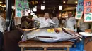 Pengusaha restoran sushi Jepang, Kiyoshi Kimura berpose dengan pedang sebelum mengiris  tuna sirip biru seberat 276 kg di restoran utamanya di Tokyo, Minggu (5/1/2020). Tuna seharga Rp 24 miliar itu disebut sebagai yang tertinggi kedua dalam rekor lelang ikan di Pasar Toyosu. (Kazuhiro NOGI / AFP)