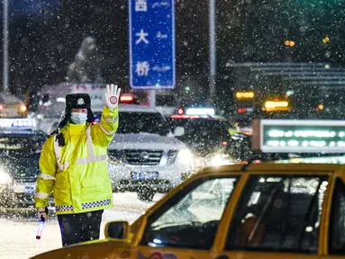 Polisi bertugas di tengah hujan salju di Urumqi, ibu kota Daerah Otonom Uighur Xinjiang, China barat laut, pada 19 November 2020. Hujan salju yang terus turun selama berhari-hari telah menyebabkan jalanan di Kota Urumqi basah dan licin. (Xinhua/Wang Fei)
