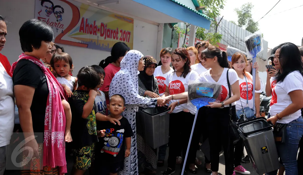 Relawan dari Gerakan Aksi Srikandi Coblos Ahok (Gadis Ahok) memberikan sapu dan tempat sampah ke warga di kawasan Cipete, Jakarta Selatan, Senin (26/12). Sebanyak 150an kantong sampah dan sapu dibagikan ke warga. (Liputan6.com/Gempur M Surya)