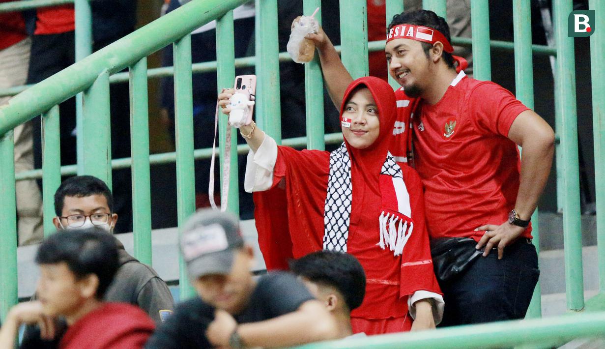 Suporter melakukan swafoto usai memberi dukungan saat Timnas Indonesia U-19 melawan Brunei Darussalam pada laga kedua Grup A Piala AFF U-19 2022 di Stadion Patriot Candrabhaga, Bekasi, Senin (4/7/2022). (Bola.com/M Iqbal Ichsan)