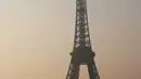 Sejumlah wisatawan saat menikmati matahari terbit di dekat menara Eiffel, Paris (11/3/2016). (AFP/Ludovic MARIN)