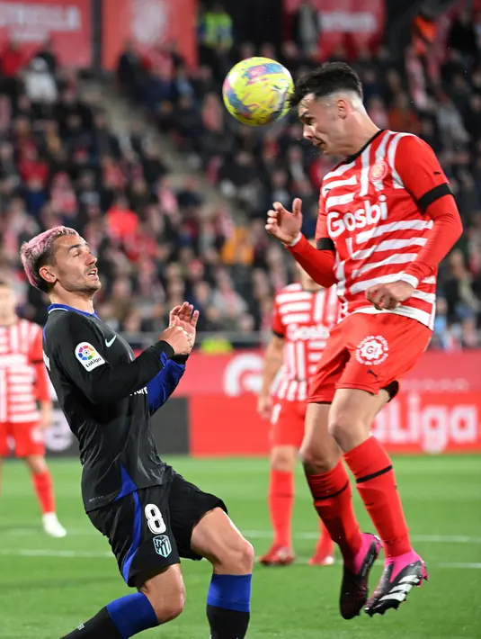 <p>Pemain Atletico Madrid Antoine Griezmann (kiri) bersaing memperebutkan bola dengan pemain Girona Arnau Martinez pada pertandingan sepak bola Liga Spanyol di Stadion Montilivi, Girona, Spanyol, 13 Maret 2023. Gol tunggal Alvaro Morata membawa Atletico Madrid mengalahkan Girona. (LLUIS GENE/AFP)</p>