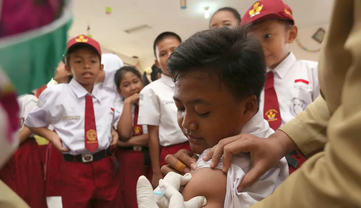 Siswa SD saat disuntik imunisasi difteri di sebuah sekolah dasar di Tangerang,  Senin (11/12). Indonesia memulai sebuah kampanye untuk mengimunisasi 8 juta anak-anak dan remaja dari difteri. (AP Photo / Tatan Syuflana)