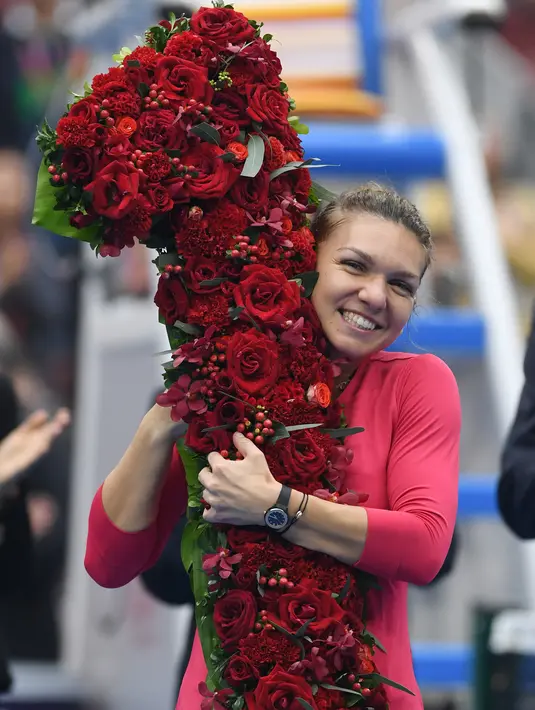 Petenis Rumania, Simona Halep memeluk buket bunga berbentuk angka satu saat merayakan kemenangan atas Jelena Ostapenko (Latvia) pada semifinal China Terbuka 2017 di Beijing, Sabtu (7/1). Halep naik ke posisi teratas WTA kali pertama. (GREG BAKER / AFP)