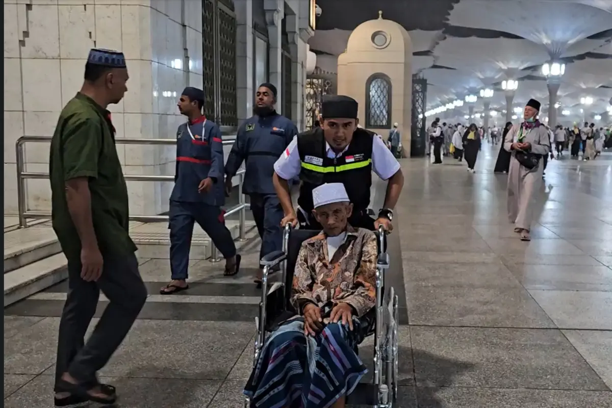 Petugas haji mengantar pulang jemaah haji lansia dari Masjid Nabawi menuju hotel menggunakan kursi roda.  (FOTO: MCH PPIH ARAB SAUDI 2023)