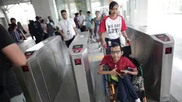 Petugas membantu penyandang disabilitas melintasi "Gate Elektronik" di Stasiun LRT Veldrome, Jakarta, Sabtu (27/4). Kegiatan yang diikuti Jakarta Barrier Free Tourism (JBFT) tersebut untuk mengenalkan kereta Lintas Rel Terpadu (LRT)  lebih dekat kepada masyarakat. (Liputan6.com/Faizal Fanani)