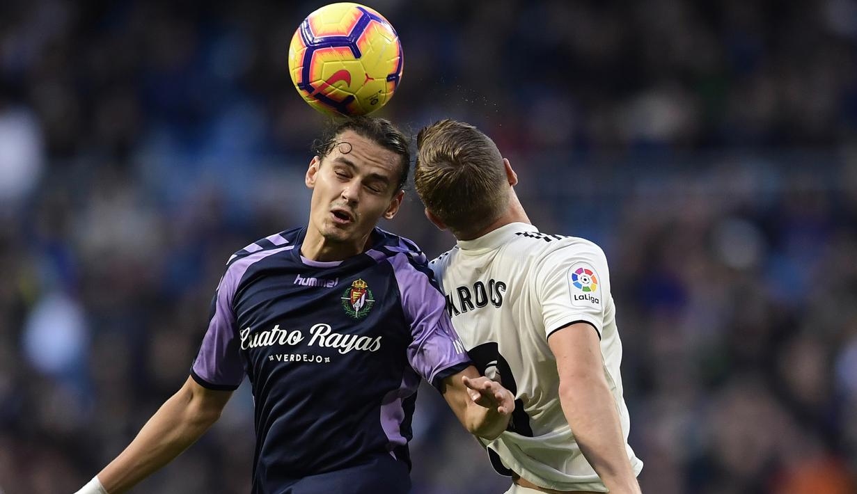 Striker Real Valladolid, Enes Unal, duel udara dengan gelandang Real Madrid, Toni Kroos, pada laga La Liga Spanyol di Stadion Santiago Bernabeu, Madrid, Sabtu (3/11). Madrid menang 2-0 atas Valladolid. (AFP/Javier Soriano)