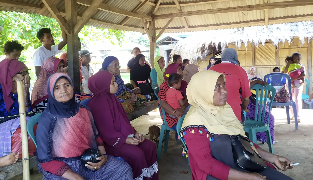 Orang-orang menunggu di tempat penampungan sementara setelah gempa bumi di Adonara, Indonesia, Selasa (14/12/2021). Peringatan dini tsunami ini dicabut usai BMKG mengamati tidak ada gempa susulan dalam 2 jam terakhir. (AP Photo)