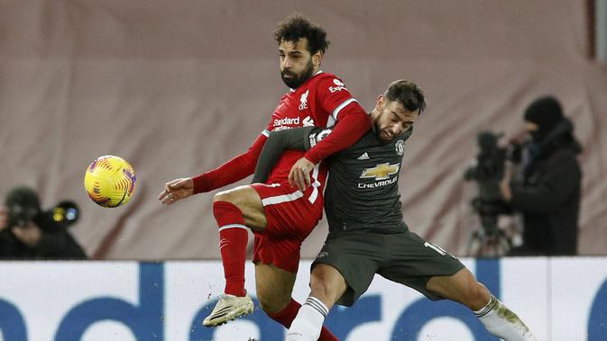 Penyerang Liverpool, Mohamed Salah berebut bola dengan gelandang Manchester United, Bruno Fernandes pada pertandingan lanjutan Liga Inggris di Stadion Anfield, Senin (18/1/2021). MU sekarang memiliki 37 poin sedangkan Liverpool 34. (Phil Noble/Pool via AP)