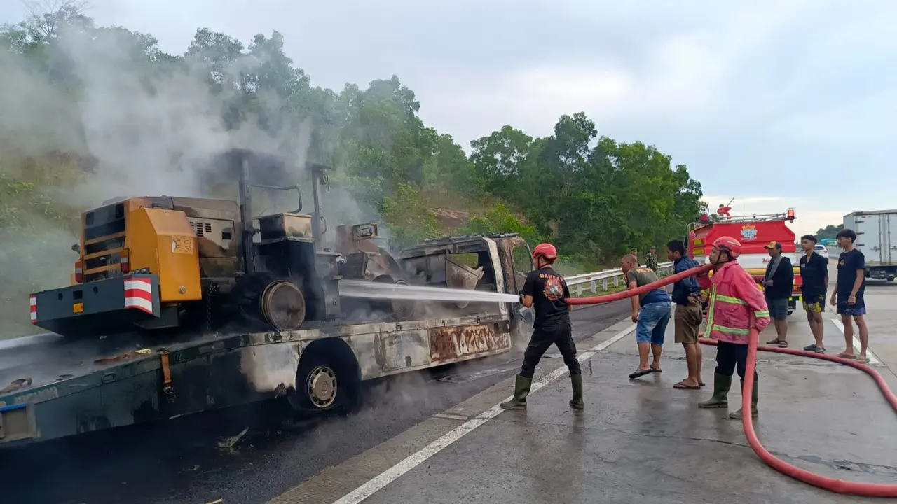 Proses pemadaman mobil towing mengangkut alat berat terbakar di Tol Lampung.