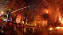 Seorang petugas pemadam memadamkan api yang membakar patung saat festival tradisional Fallas di Valencia, Spanyol (19/3). Perayaan ini berawal sejak zaman pertengahan di mana musim semi dirayakan dengan api unggun. (AP/Alberto Saiz)