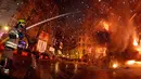 Seorang petugas pemadam memadamkan api yang membakar patung saat festival tradisional Fallas di Valencia, Spanyol (19/3). Perayaan ini berawal sejak zaman pertengahan di mana musim semi dirayakan dengan api unggun. (AP/Alberto Saiz)