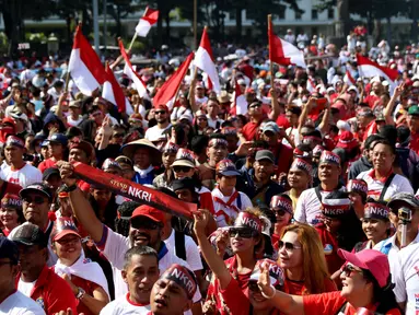 Sejumlah peserta menggunakan ikat kepala yang bertuliskan Stand of NKRI dan membawa bendera merah putih saat mengikuti aksi Parade Bhineka Tunggal Ika di kawasan Patung Kuda, Jalan MH Thamrin, Jakarta Pusat, Sabtu (19/11). (Liputan6.com/Gempur M. Surya)