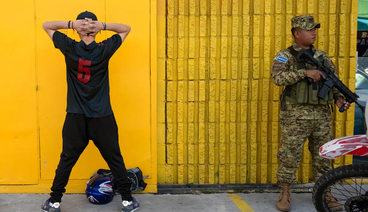 Personil militer menjaga seorang pemuda yang ditahan dalam operasi keamanan menjelang pemilihan presiden dan legislatif di San Salvador pada 1 Februari 2024. (Yuri CORTEZ/AFP)