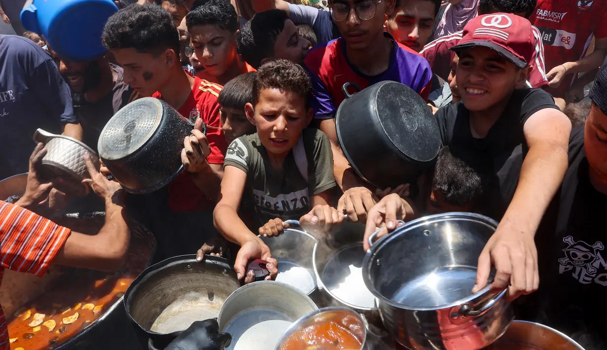 Warga Palestina berusaha mendapatkan makanan di dapur umum yang menyediakan makanan hangat di lingkungan Rimal, kota Gaza pada 18 Juni 2025. (Omar AL-QATTAA/AFP)