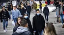 Orang-orang dengan masker melintasi jalan di pusat kota Amsterdam, Belanda, Rabu (3/11/2021). Dengan aturan terbaru, pemerintah Belanda mewajibkan penggunaan masker di ruang-ruang publik seperti tempat perbelanjaan, perpustakaan, salon, stasiun kereta, hingga rumah sakit. (Ramon van Flymen/ANP/AFP)